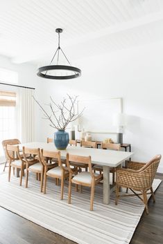 the dining room table is surrounded by wicker chairs and an oval chandelier