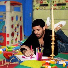 a man laying on the floor in front of a birthday cake with candles and crayons