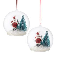 two snow globes with santa clause and trees in the snow, hanging from red string