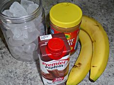 two bananas and some ice cubes on a counter next to a jar of peanut butter