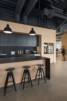 an open kitchen with black counter tops and stools