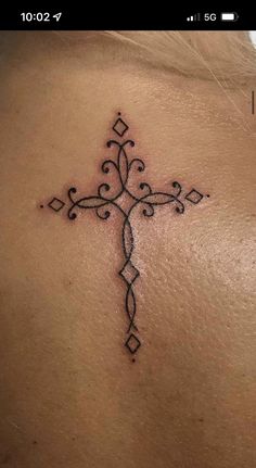 a cross tattoo on the back of a woman's upper back and shoulder area