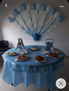 a blue table topped with plates of food and balloons in the shape of an airplane