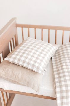 two pillows sitting on top of a wooden crib next to a pillow case with a checkered pattern