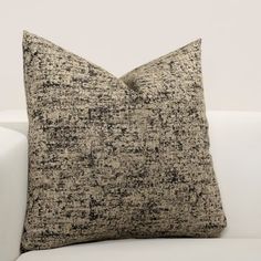 a black and white pillow sitting on top of a white couch next to a wall