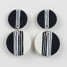 three black and white striped earrings on a white surface with one earring in the shape of a circle