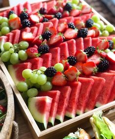 watermelon, grapes and blackberries are arranged on a platter for a party