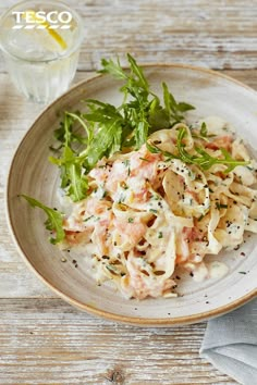 a white plate topped with pasta covered in sauce and garnished with green leaves