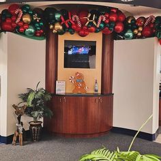 an office decorated for christmas with ornaments and decorations on the front desk, along with a flat screen tv