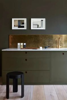 an image of a kitchen with green cabinets and gold backsplash on the wall