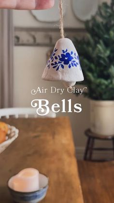 an air dry clay bell ornament hanging from a string on a wooden table