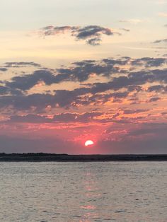 the sun is setting over the ocean with clouds in the sky and water below it