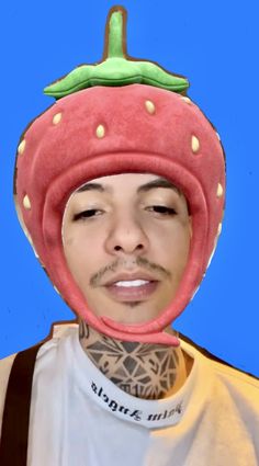 a man wearing a strawberry shaped hat on top of his head with tattoos and piercings