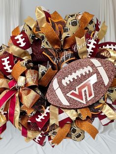 a football wreath on top of a bed with gold and red ribbons in the shape of a football