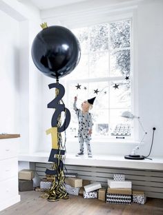 a child is standing on the window sill with a balloon in front of him