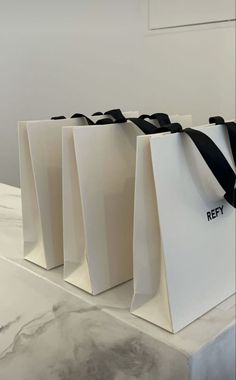 four white bags with black handles are sitting on a counter