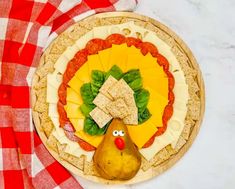 a pizza with cheese, lettuce and a turkey on it next to a red checkered table cloth