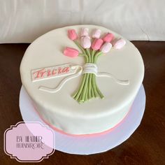 a white cake decorated with pink and green tulips on a plate that says treata