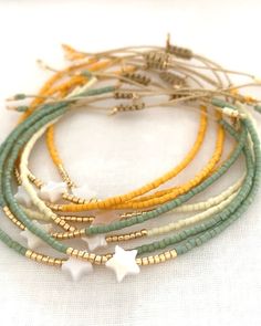 several bracelets with white stars and green beads on top of each other in various colors