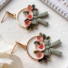 two earrings with flowers on them sitting next to each other