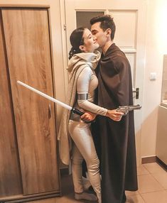 a man and woman dressed as star wars characters kissing each other in front of a door