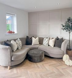 a living room filled with lots of furniture and pillows on top of wooden flooring