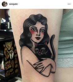 a woman holding a cat on her arm with the caption, i am not sure what this tattoo is