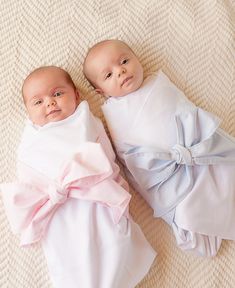 two baby babies laying next to each other on a white blanket covered in pink bows