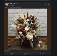 a bouquet with feathers and flowers on top of a wooden table next to a brick wall