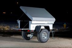 an off - road camper is parked on the side of the road at night