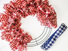 a red, white and blue ribbon wreath next to a pair of scissors