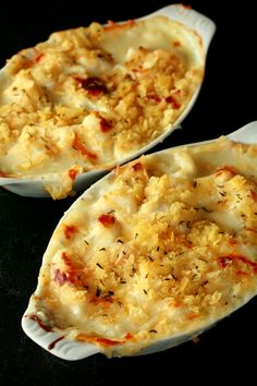 two servings of baked potato casserole on a black surface with sprinkled parmesan cheese