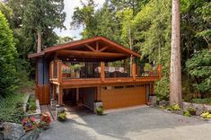 a large house with a garage in the middle of some trees and bushes around it