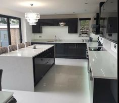 a large kitchen with black cabinets and white counter tops is seen in this image from the dining room