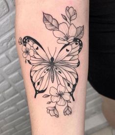 a black and white butterfly with flowers on it's back leg, tattoo style