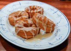 glazed donuts with icing on a blue and white plate sitting on a wooden table