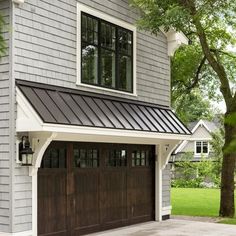 a gray house with two brown garage doors and a white trim on the side of it