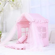 a pink bed with a canopy and curtains on the top is in front of a white wall