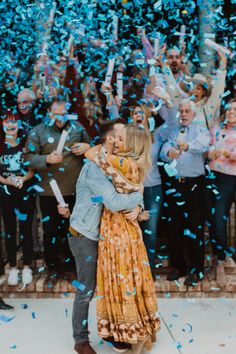 a man and woman hug as confetti is thrown in the air behind them