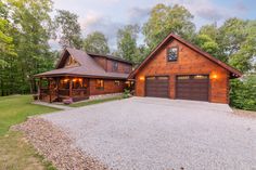 a large house with two garages in front of it and lots of trees around