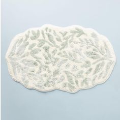 a white bath mat with green leaves on it and a light blue wall in the background