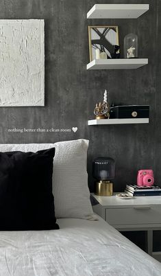 a white bed topped with pillows next to shelves