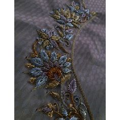 a close up view of an embroidered fabric with gold and blue flowers on the side