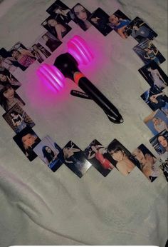 a pink light up hair brush laying on top of a bed next to some photos