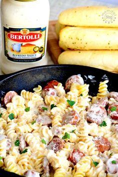 a skillet filled with pasta and meat next to bread