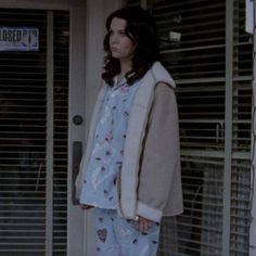 a woman standing in front of a door wearing pajamas