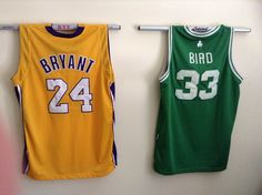 two green and yellow basketball jerseys hang on the wall next to each other in front of a white background