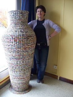 a woman standing next to a large vase