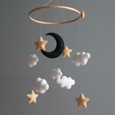 a crib mobile with stars, clouds and a crescent hanging from the ceiling above it