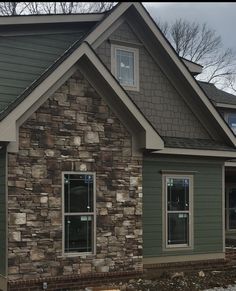 a house that is being built with some siding on the side and windows in front